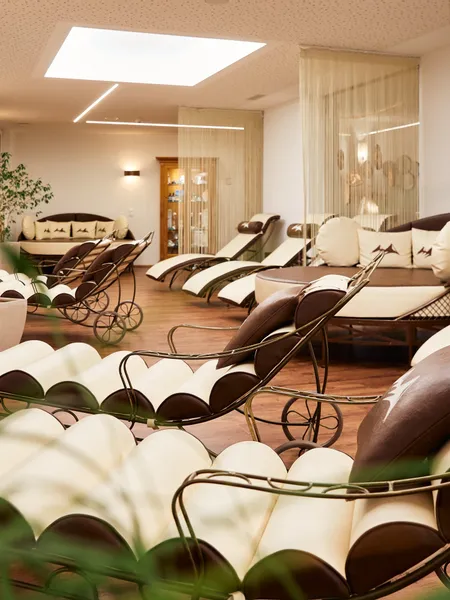 Saunabereich und Ruheraum Eleganter Wellnessbereich mit komfortablen Relaxliegen und Pflanzen im warmen Licht